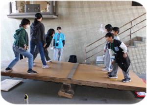 ジャンボシーソーの上でバランスを取っている写真です